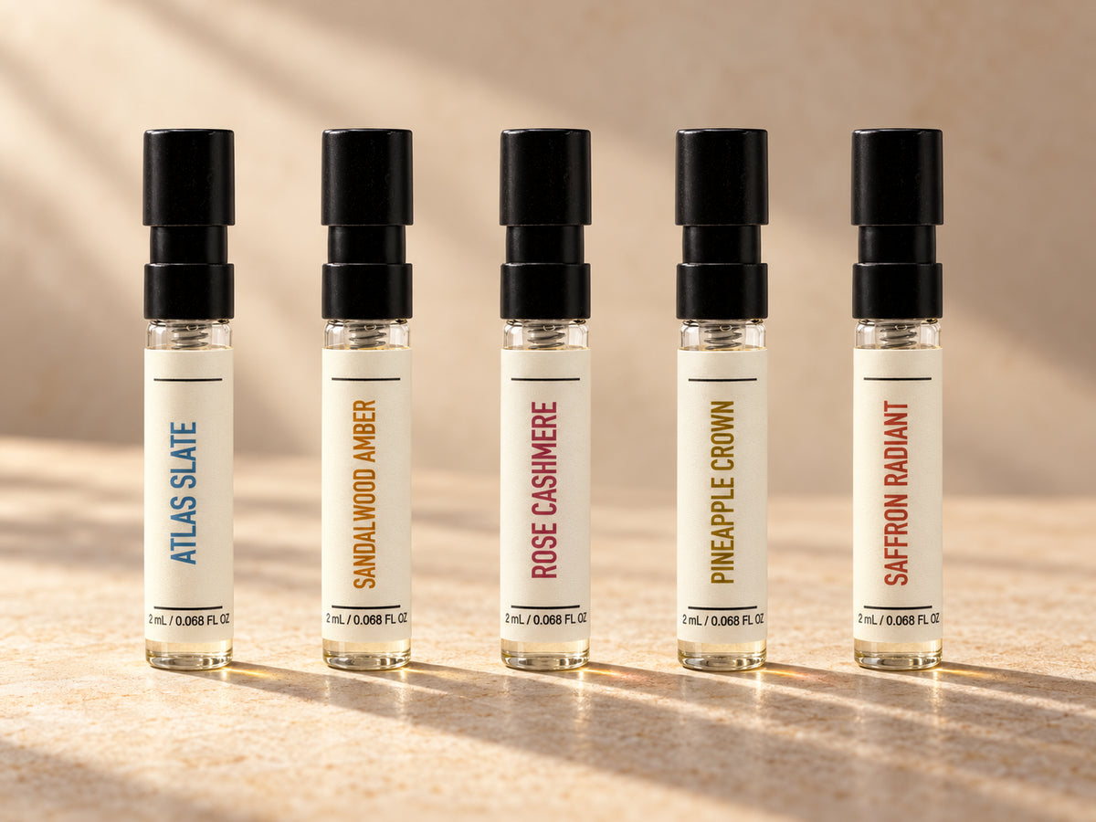AI-enhanced lineup detail showing five included fragrances: Atlas Slate, Sandalwood Amber, Rose Cashmere, Pineapple Crown and Saffron Radiant. Try It All contains 26 separate 2 mL vials; the full set is not pictured.
